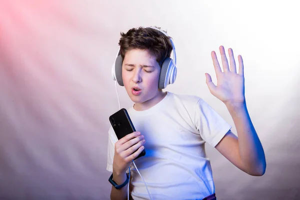 当一个年轻人用手机在耳机里听他最喜欢的音乐时 他的情绪和快乐 一个穿着白色T恤 背景为各种浅紫色的年轻人的照片 — 图库照片