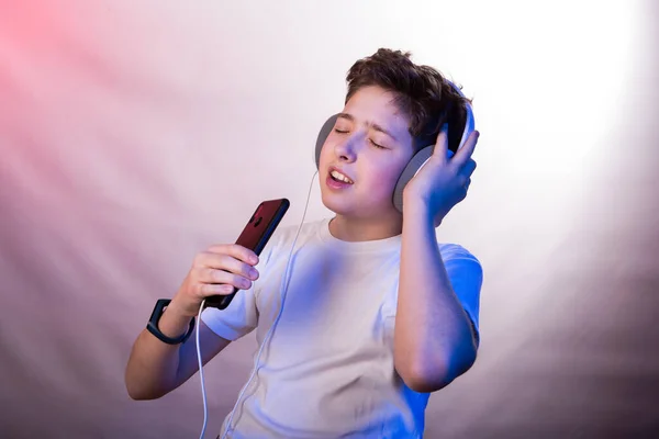 전화를 사용하여 헤드폰으로 음악을 젊은이의 즐거움 티셔츠를 남성의 보라색 색조의 — 스톡 사진