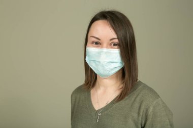 Karantina ve tecrit sırasında maske iletişimi engellemez. Diğer insanlarla iletişim kurarken yeşil arka planda maske takan genç ve güzel bir kadının duyguları..