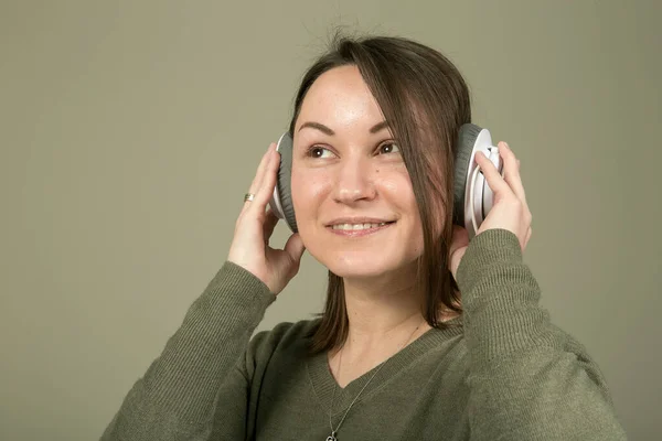 How to spend time during quarantine and isolation? Listen to your favorite music. The emotions and enjoyment of a young and beautiful woman in green, listening to her favorite music.