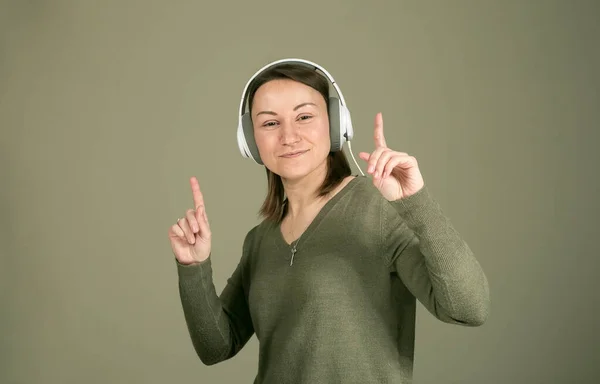 How to spend time during quarantine and isolation? Listen to your favorite music. The emotions and enjoyment of a young and beautiful woman in green, listening to her favorite music.