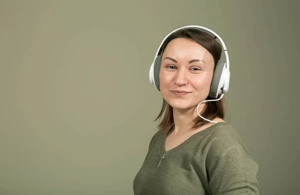 How to spend time during quarantine and isolation? Listen to your favorite music. The emotions and enjoyment of a young and beautiful woman in green, listening to her favorite music.