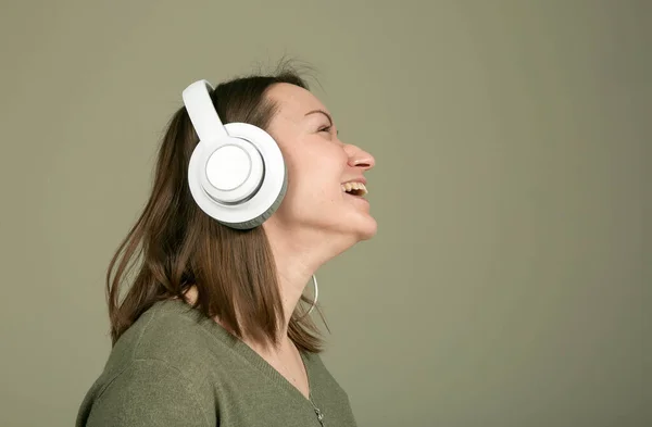 How to spend time during quarantine and isolation? Listen to your favorite music. The emotions and enjoyment of a young and beautiful woman in green, listening to her favorite music.