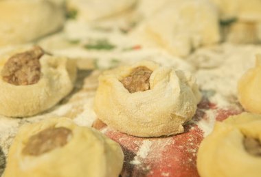 Karantina ve izolasyon süresince evde nasıl zaman geçireceksin? Ukrayna tarifine göre belyashes pişir. Altıncı adım. Kızartmaya hazır belyashes beyaz özel bir masa örtüsü üzerinde.