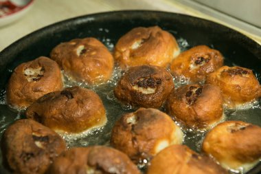 Karantina ve izolasyon süresince evde nasıl zaman geçireceksin? Yemek pişirmek için hobiler. Adım 8. Belyashlar yüksek sıcaklıkta kızartılmış tavada köpüren sebze yağıyla pişirilir ve eller onları çatalla çevirir.