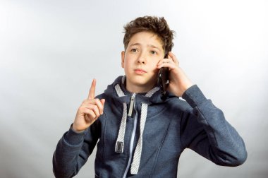 Cep telefonu kullanan genç bir adamın duyguları ve neşesi. Gri spor ceketli genç bir adamın resmi. Arka planda baskın ışık gölgeleri var.