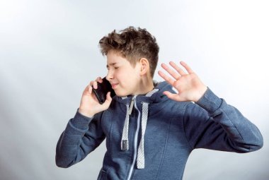 Cep telefonu kullanan genç bir adamın duyguları ve neşesi. Gri spor ceketli genç bir adamın resmi. Arka planda baskın ışık gölgeleri var.