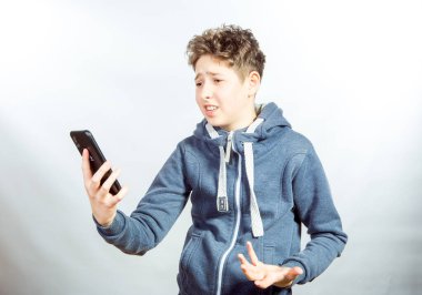 Cep telefonu kullanan genç bir adamın duyguları ve neşesi. Gri spor ceketli genç bir adamın resmi. Arka planda baskın ışık gölgeleri var.