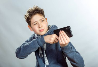 Cep telefonu kullanan genç bir adamın duyguları ve neşesi. Gri spor ceketli genç bir adamın resmi. Arka planda baskın ışık gölgeleri var.