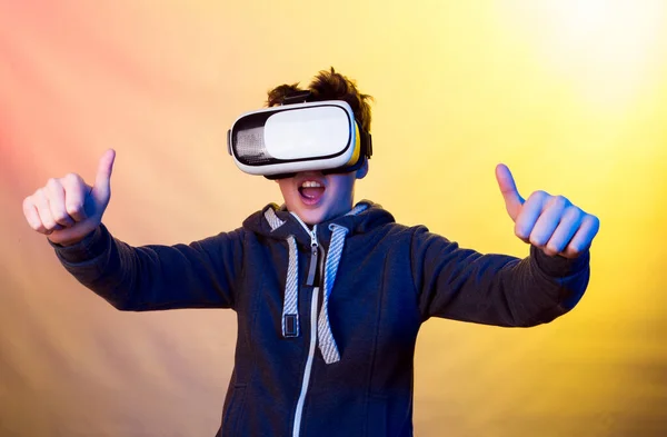 Emotions and joy of a young man when using virtual reality. Photo of a young man in a dark sports jacket on a background of prevailing yellow and light purple shades