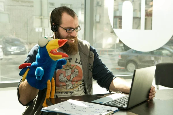 Online lesson. A young man conducts an online lesson during quarantine. As a visual aid, he uses a toy.