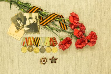 Zafer Günü. Atalarımızın başarısını hatırlıyoruz. Siparişler ve madalyalar, savaş mektupları, arka planda kırmızı karanfillerin fotoğrafları..
