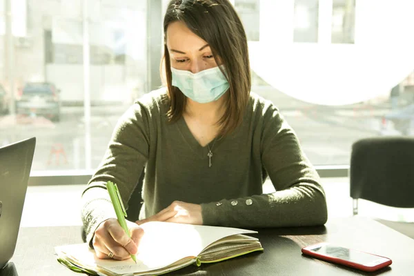 An online lesson during quarantine. Young teacher in medical mask conduct an online lesson.