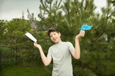 Karantinadan sonra doğadaki genç bir adamın neşesi. Çocuk sevinçten zıplıyor ve gereksiz tıbbi maske ve eldivenleri atıyor..