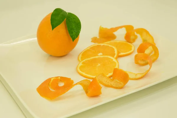 Oranges. Oranges, orange slices on a white plate. Isolated on a white background.
