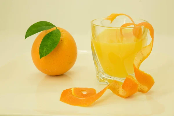 Orange and orange juice. Orange with a green leaf and a glass of orange juice are decorated with orange zest. Isolated on a white background.