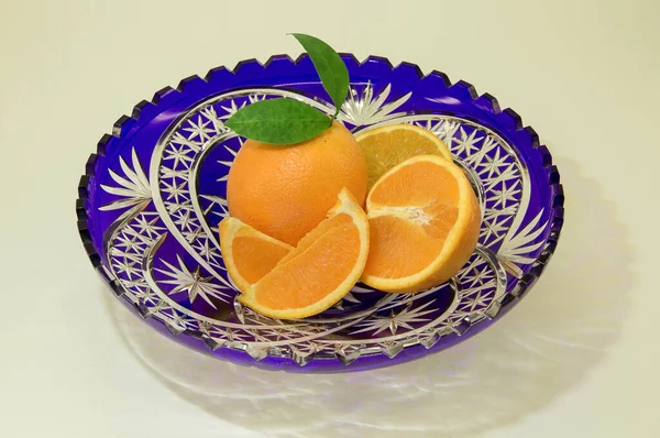 Orange and slices of orange. Orange with green leaf and slices of orange on a red crystal dish. Isolated on a white background.