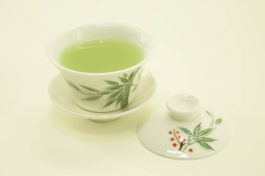 Japon çayı. Matcha latte çayı. Geleneksel oryantal fincanda çay ve çay tabağı. Beyaz arka planda beyaz bir kasede izole edilmiş..