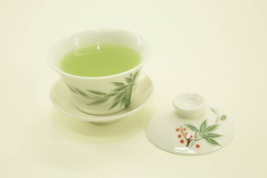 Japon çayı. Matcha latte çayı. Geleneksel oryantal fincanda çay ve çay tabağı. Beyaz arka planda beyaz bir kasede izole edilmiş..