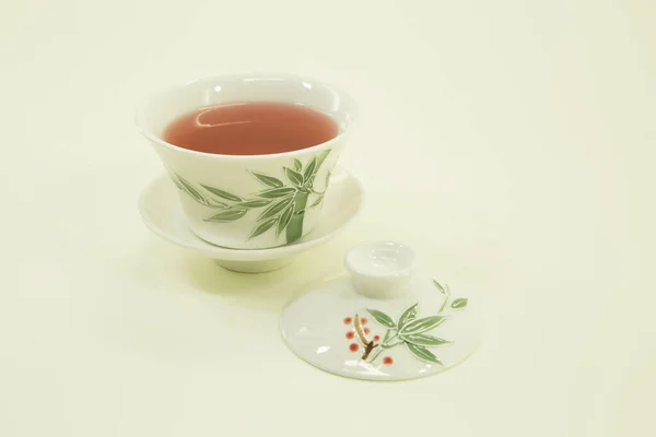 Chinese tea. Chinese fruit tea with hibiscus.The fruit tea in a beautiful traditional oriental cup with saucer. Isolated in a white bowl on a white background.