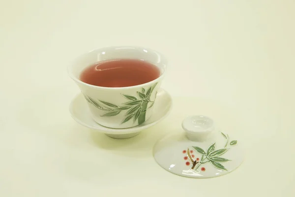 Chinese tea. Chinese fruit tea with hibiscus.The fruit tea in a beautiful traditional oriental cup with saucer. Isolated in a white bowl on a white background.