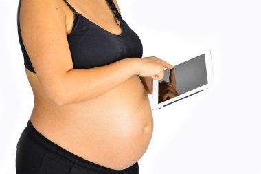 Hamileliğinin sonlarına doğru beyaz bir iPad kullanan bir kadın..