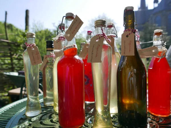 Farklı şekillerde ve boyutlarda şişeler çeşitli organik sıvılarla doldurulmuş. İçinde ravent, mürver çiçeği ya da manolya var..