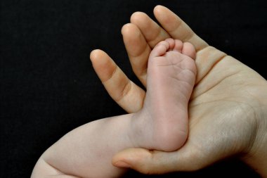 siyah bir arka plan üzerinde izole motherhand ve bebek ayak