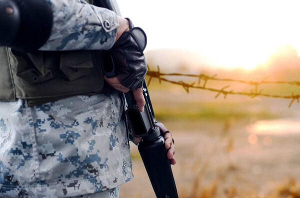 Selected focus army with rifle gun with blurred background wire 