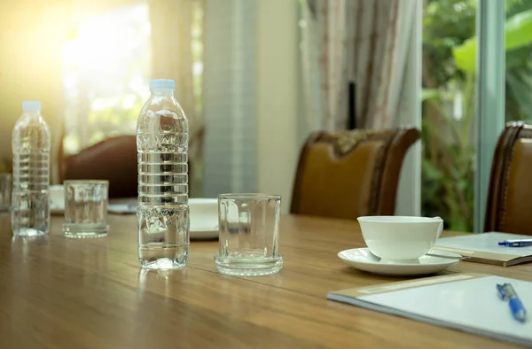Garrafas de água e xícara de café em mesa de madeira em conferência — Fotografia de Stock