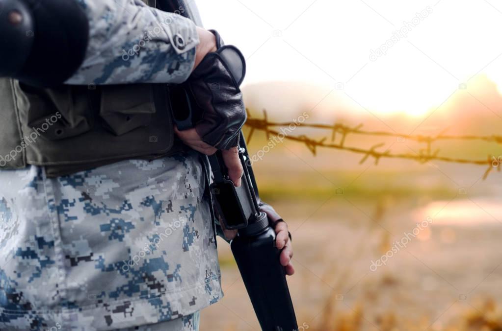 Selected focus army with rifle gun with blurred background wire 