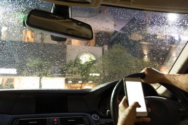 Araba ve gece yağmur sırasında cep telefonu kullanan adam