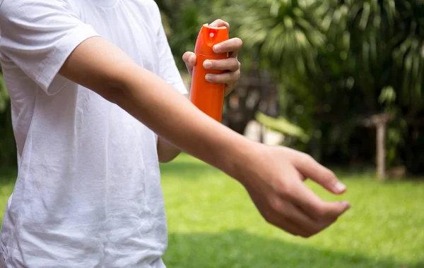 Young boy spraying insect repellents on skin in the garden — Stock Photo, Image