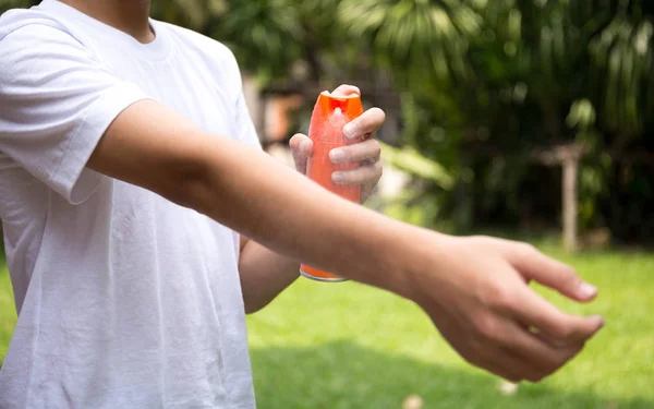 Jovem menino pulverizando repelentes de insetos na pele com frasco de spray — Fotografia de Stock