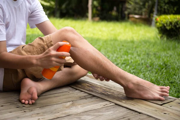 Young boy spraying insect repellents on his leg  with spray bott — Stock Photo, Image