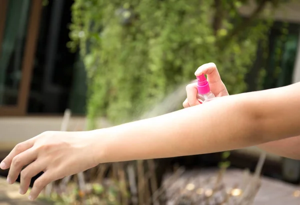 Woman spraying insect repellents on skin in the garden — Stock Photo, Image