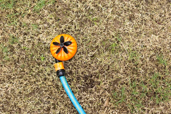 Оранжевый дождеватель в сухой траве — стоковое фото