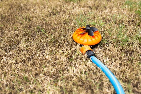 Aspersor de naranja en hierba seca — Foto de Stock