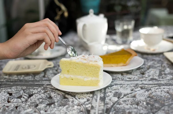 ヴァルで紅茶のカップとココナッツ ケーキを食べるスプーンを保持している女性 — ストック写真
