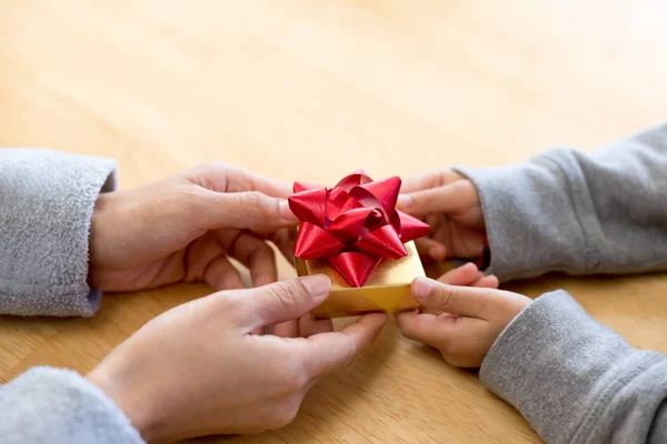 Young child handing a gift box to mum — Stock Photo, Image