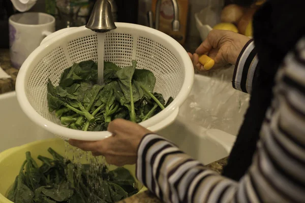 Mujer lavando verdura verde en canasta blanca en un fregadero de cocina — Foto de Stock