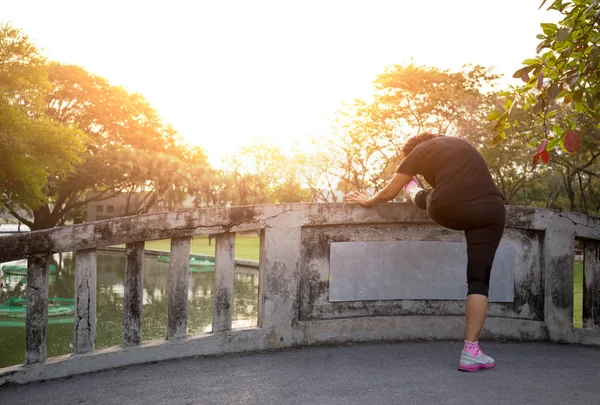 Mujer haciendo ejercicio de estiramiento en el puente en el parque — Foto de Stock