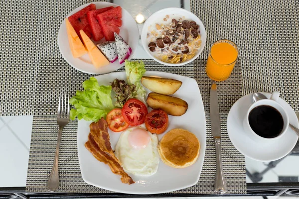 Frukost på bordet med pannkakor, bacon, ägg och kaffe — Stockfoto