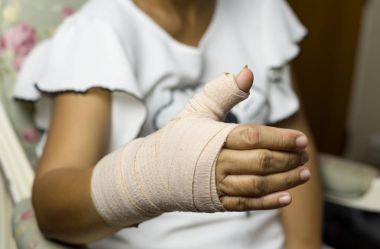 Elinde kemik kırık tahta ile bir sandalyede oturan kadın