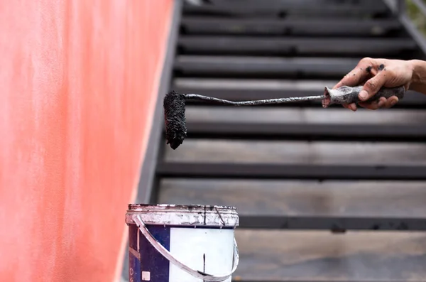 Hombre mano sosteniendo rodillo de pintura y un cubo — Foto de Stock