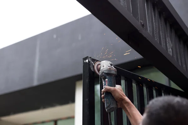 Ruce drží ocelové řezná bruska pracuje na kovové dveře — Stock fotografie