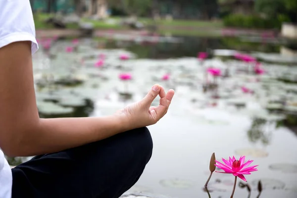 Mujer haciendo meditación de yoga junto al estanque de loto — Foto de Stock