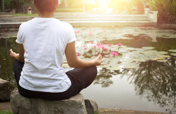 Mujer haciendo meditación de yoga junto al estanque de loto — Foto de Stock