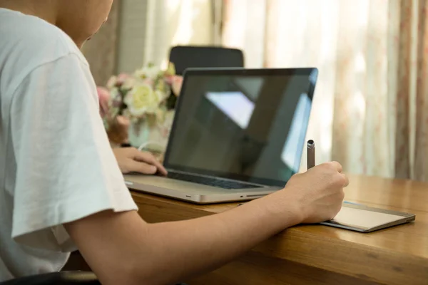 Teenage student working on laptop on wooden table — Stock Photo, Image