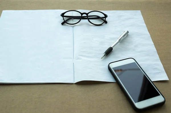 Valda fokus penna och glasögon och mobiltelefon med manuell bok — Stockfoto